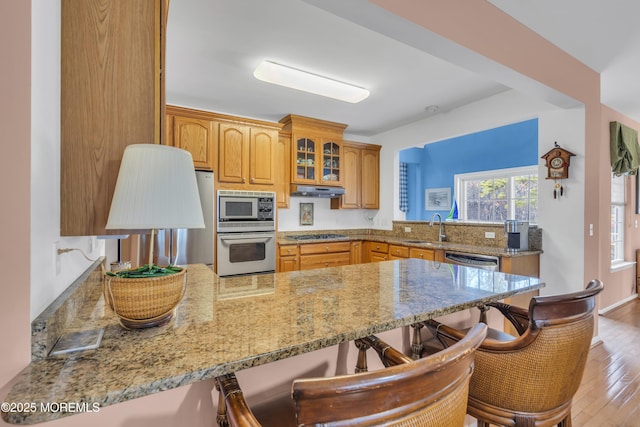kitchen featuring stainless steel appliances, a breakfast bar area, a peninsula, and a sink