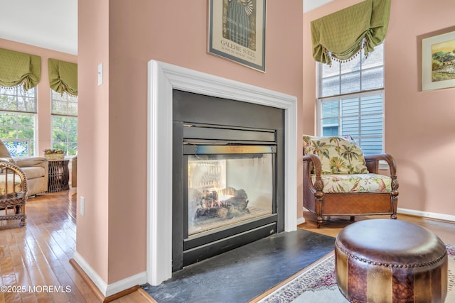 living area with hardwood / wood-style floors, baseboards, and a wealth of natural light