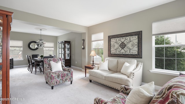 living area featuring baseboards, a notable chandelier, and light carpet