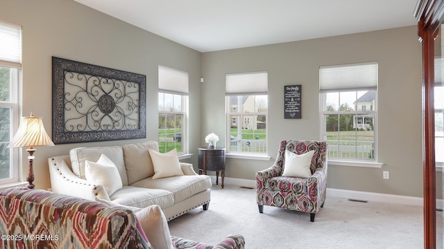 carpeted living area featuring a wealth of natural light, visible vents, and baseboards
