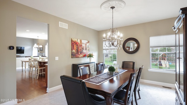 dining room featuring baseboards, a wealth of natural light, a notable chandelier, and light colored carpet