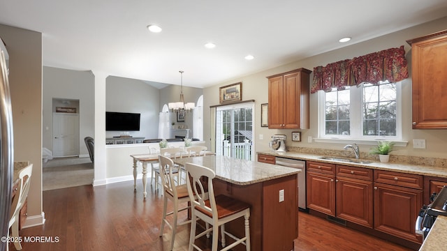 kitchen featuring a sink, a notable chandelier, light stone counters, dishwasher, and range