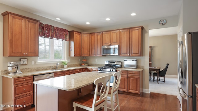 kitchen featuring stainless steel appliances, a sink, dark wood finished floors, recessed lighting, and brown cabinetry