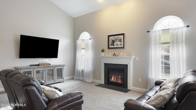 living room with a fireplace with flush hearth, baseboards, vaulted ceiling, and carpet flooring