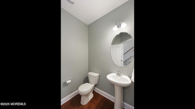 bathroom with a sink, toilet, baseboards, lofted ceiling, and wood finished floors