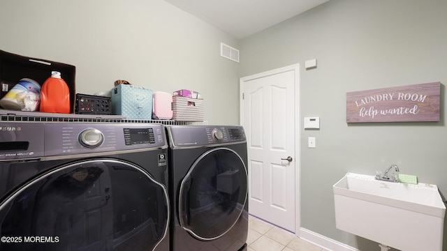 clothes washing area with a sink, light tile patterned floors, washer and dryer, laundry area, and visible vents