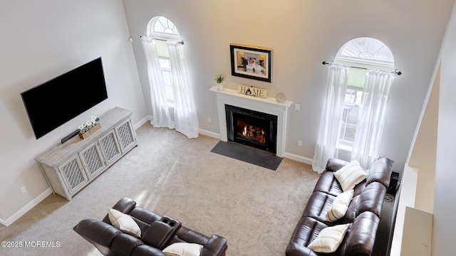 living room with a fireplace with flush hearth, carpet floors, and baseboards