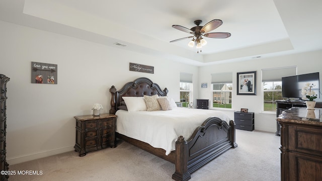 bedroom featuring multiple windows, visible vents, light colored carpet, and a tray ceiling