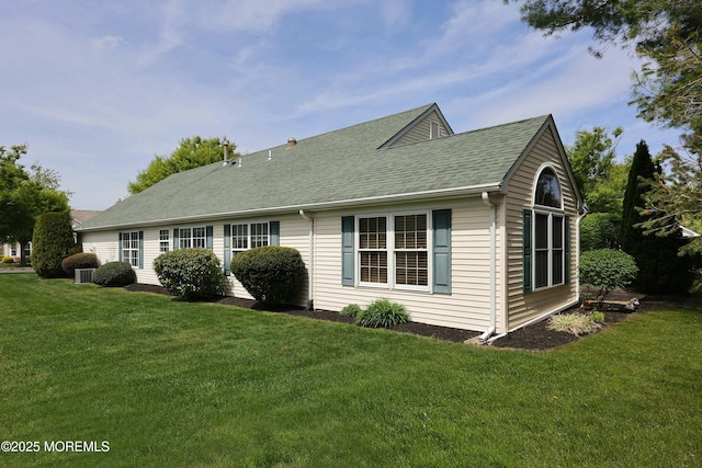 view of side of home featuring a lawn and roof with shingles