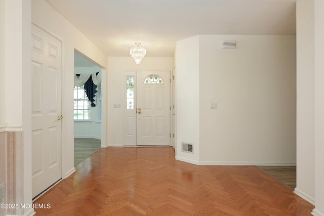 entrance foyer featuring baseboards, visible vents, and a notable chandelier