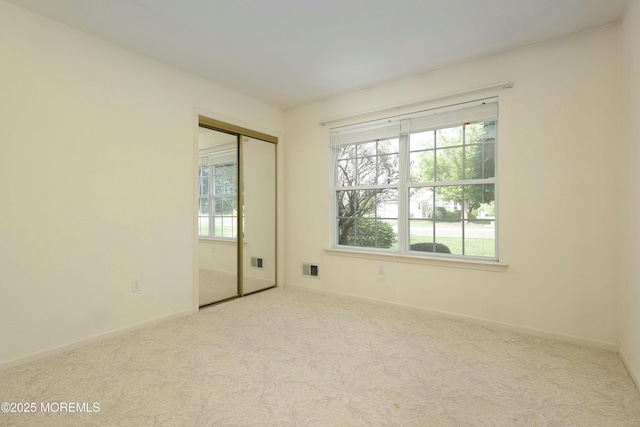 spare room with carpet floors, baseboards, and visible vents