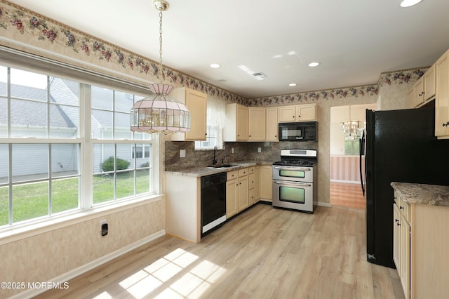 kitchen featuring a sink, decorative light fixtures, baseboards, light wood-type flooring, and black appliances