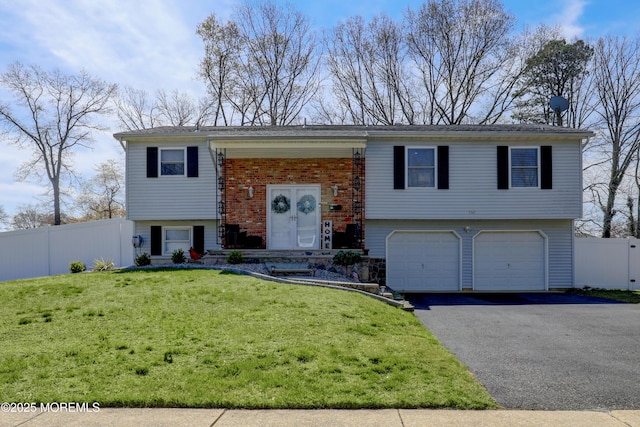 split foyer home with an attached garage, driveway, fence, and a front yard