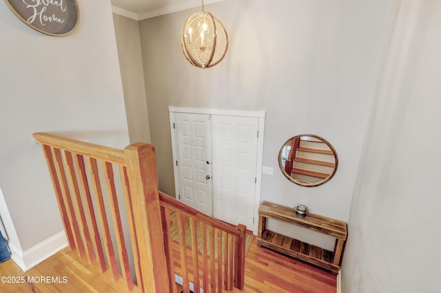 stairs with baseboards, wood finished floors, and ornamental molding