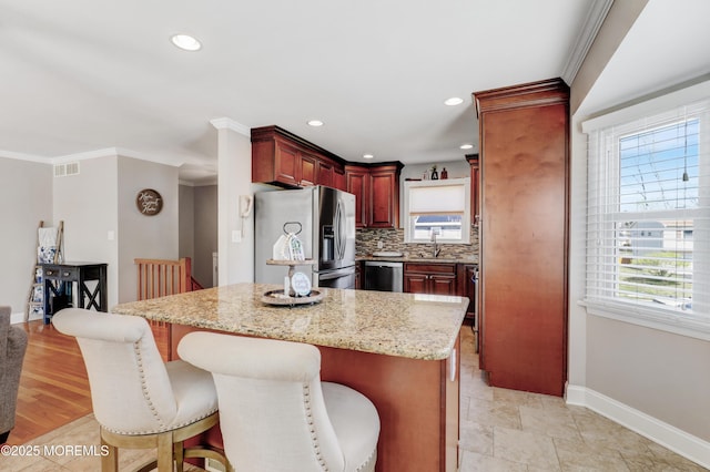 kitchen featuring stainless steel appliances, visible vents, reddish brown cabinets, a sink, and baseboards