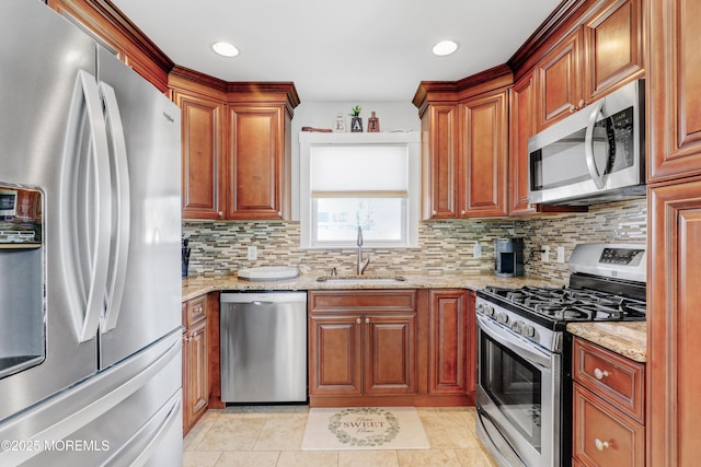 kitchen with decorative backsplash, light stone counters, a sink, and appliances with stainless steel finishes