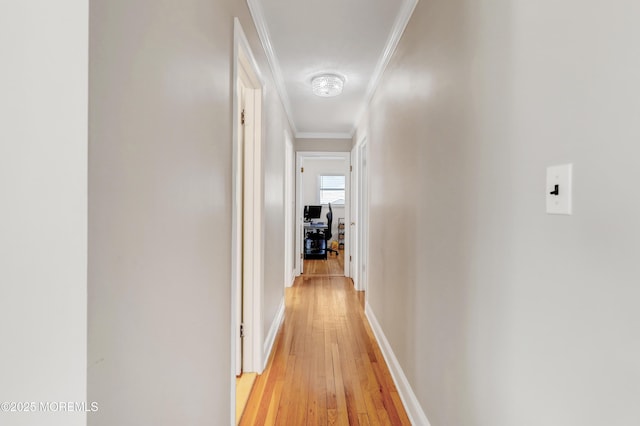 corridor featuring baseboards, ornamental molding, and light wood-style flooring