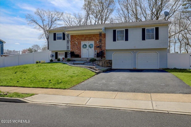 bi-level home with an attached garage, driveway, fence, and a front yard