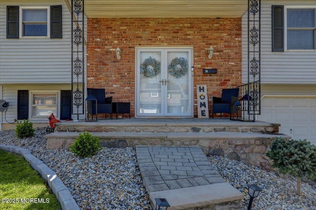 entrance to property featuring a porch, brick siding, and a garage