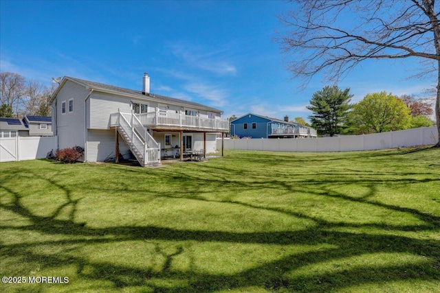 back of house featuring a chimney, stairs, a fenced backyard, a wooden deck, and a lawn