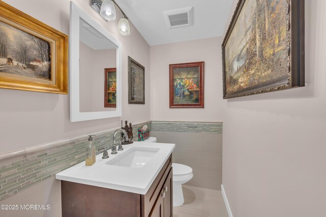 83 Parkway Dr Unit E, Freehold, NJ 07728 - half bath featuring visible vents, tile patterned flooring, vanity, toilet, and tile walls