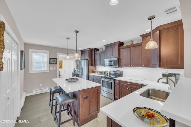 83 Parkway Dr Unit E, Freehold, NJ 07728 - kitchen with a breakfast bar, a center island, tasteful backsplash, a sink, and stainless steel appliances