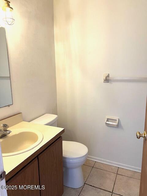 bathroom with toilet, tile patterned floors, vanity, and baseboards