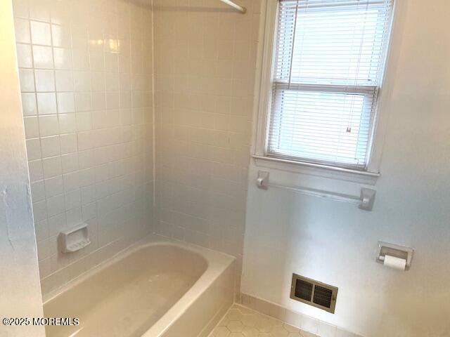 bathroom with visible vents, baseboards, tile patterned flooring, and  shower combination