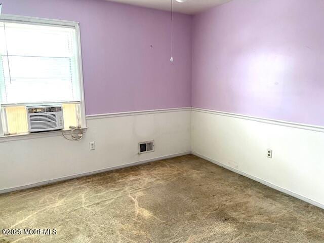 empty room with carpet floors, baseboards, cooling unit, and visible vents