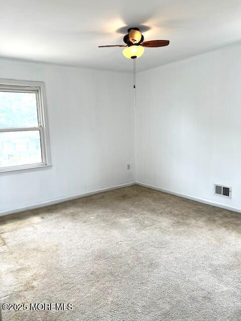 unfurnished room with visible vents, baseboards, a ceiling fan, and carpet floors
