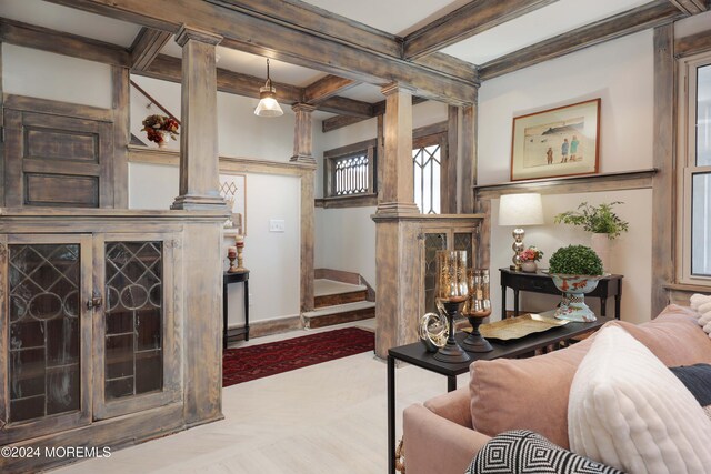living room featuring baseboards, coffered ceiling, ornate columns, beamed ceiling, and stairway