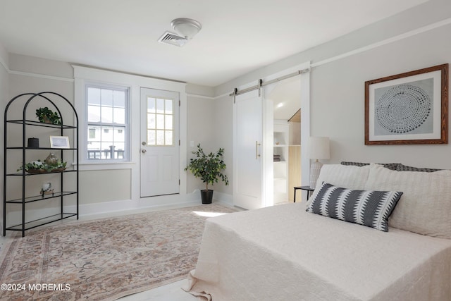 bedroom with a barn door, baseboards, and visible vents