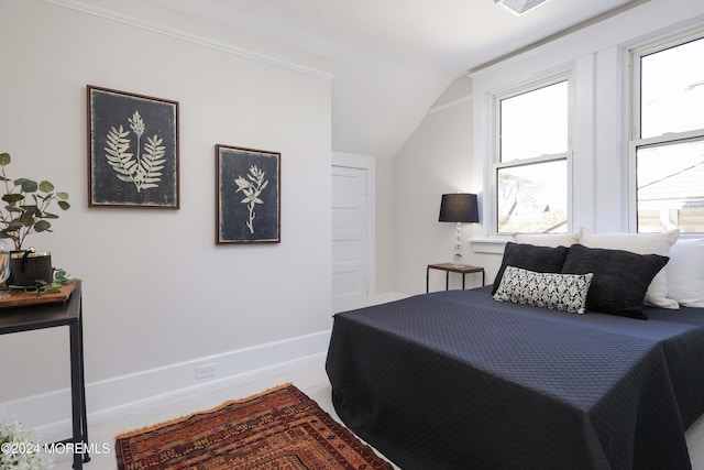 bedroom featuring vaulted ceiling, multiple windows, and baseboards