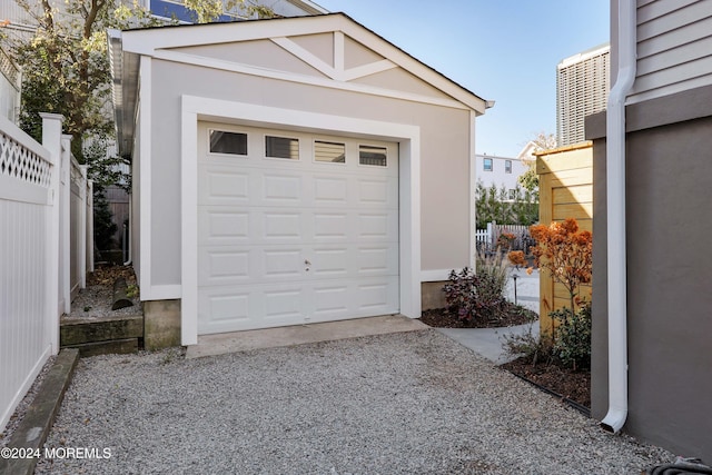 detached garage featuring fence and driveway
