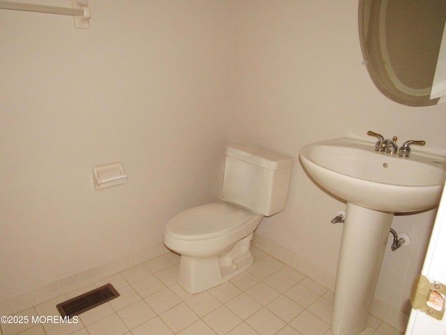 half bathroom featuring visible vents, toilet, and tile patterned floors