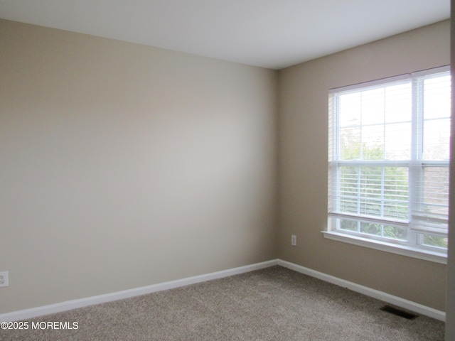 carpeted spare room with visible vents and baseboards