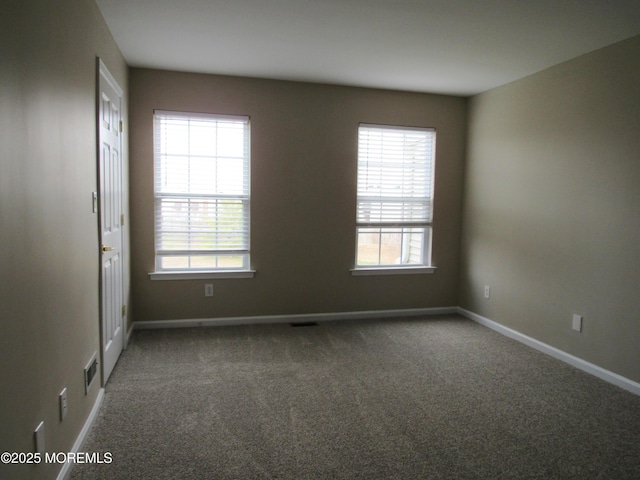 empty room featuring carpet flooring, visible vents, and baseboards
