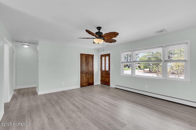 spare room featuring a baseboard heating unit, wood finished floors, visible vents, and a ceiling fan
