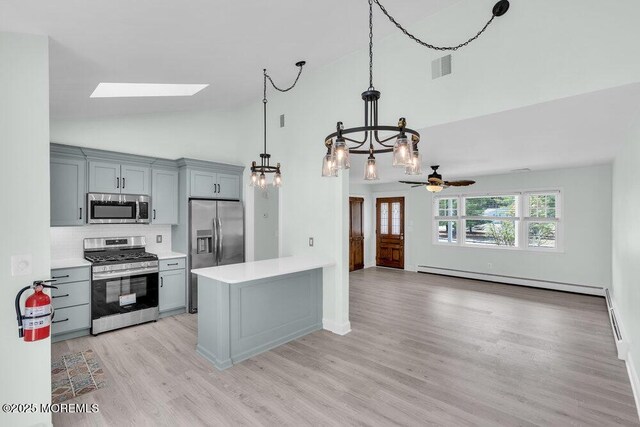 kitchen featuring stainless steel appliances, light wood-style floors, a skylight, light countertops, and high vaulted ceiling