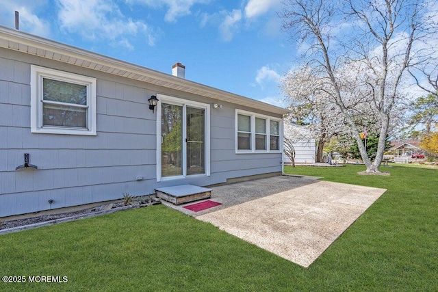 back of property with a patio area, a lawn, and a chimney