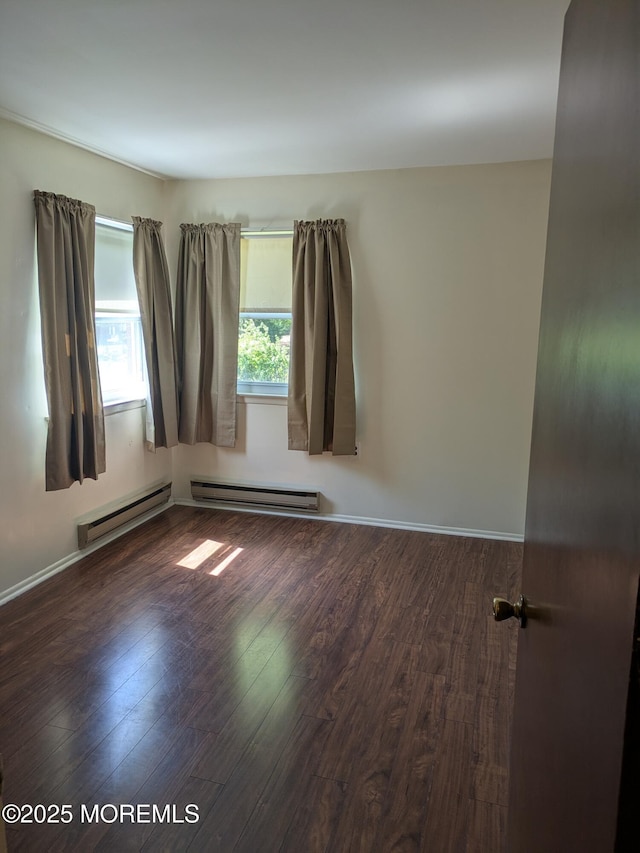 empty room with baseboards, wood finished floors, and a baseboard radiator