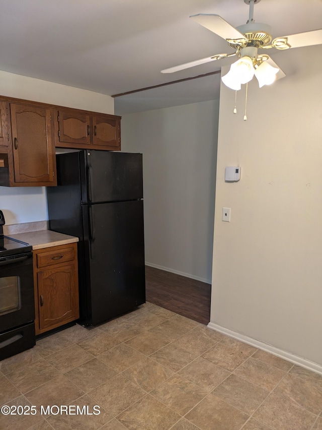 kitchen featuring brown cabinets, light countertops, a ceiling fan, baseboards, and black appliances