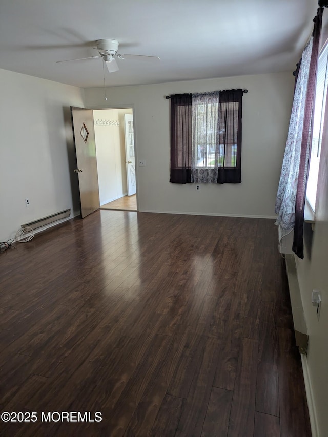 unfurnished room featuring plenty of natural light, a baseboard heating unit, ceiling fan, and wood finished floors