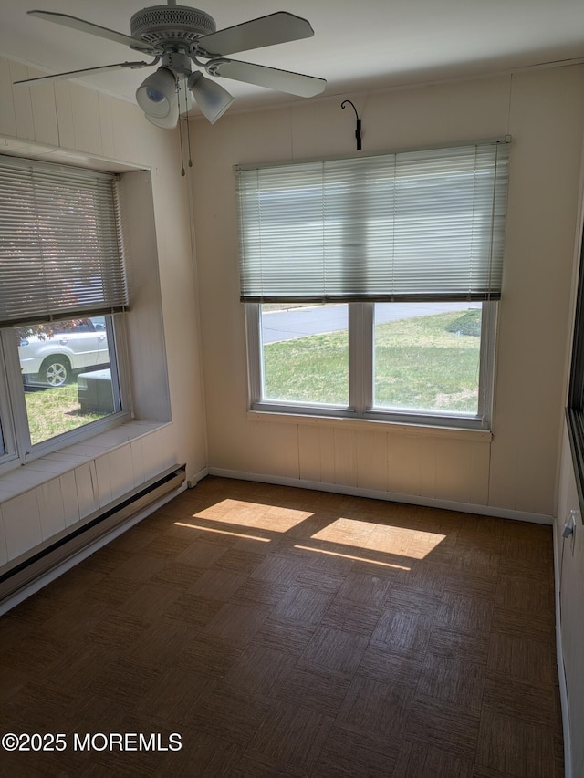 empty room featuring a ceiling fan and a baseboard heating unit