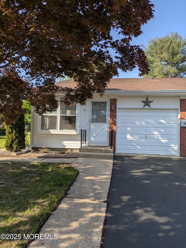 view of front of house with brick siding, driveway, a shingled roof, and a garage