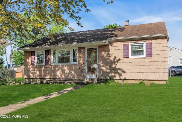 ranch-style house featuring a chimney, a shingled roof, and a front yard