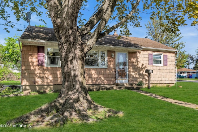 view of front of house featuring entry steps, a front yard, and roof with shingles