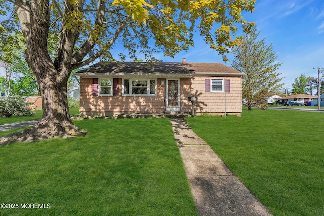view of front facade with roof with shingles and a front yard
