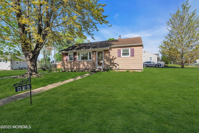 view of front of house featuring roof with shingles, a chimney, and a front yard