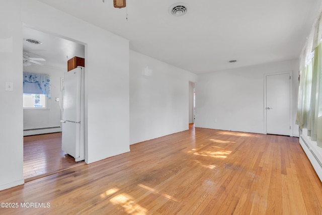 unfurnished room with a baseboard radiator, baseboard heating, a ceiling fan, light wood-type flooring, and visible vents